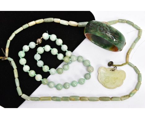 FOUR ITEMS OF JADE JEWELLERY, to include a dyed carved bangle, inner diameter 65mm, a spherical bead necklace with magnetic c
