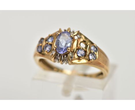 A 9CT GOLD TANZANITE AND DIAMOND DRESS RING, designed with a central claw set, oval cut tanzanite, within a single cut diamon