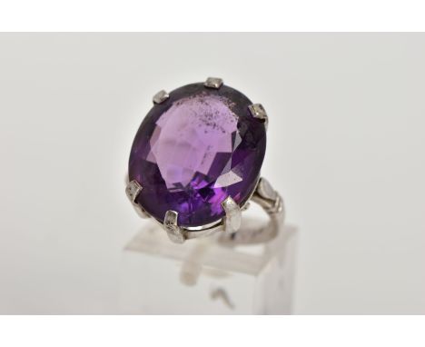 AN 18CT WHITE GOLD AMETHYST RING, the oval amethyst within a six claw setting to the plain band with banded shoulders, 18ct h