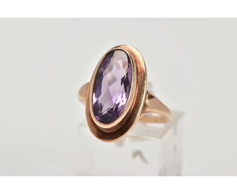 A 9CT GOLD AMETHYST DRESS RING, designed with an oval cut amethyst within a collet mount, measuring approximately 12.1mm x 4.