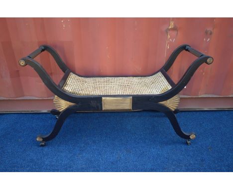 A 20TH CENTURY FRENCH EBONISED AND GILT SAVONAROLA STOOL, with a bergère seat, length 118cm x depth 40cm x height 67cm (the i