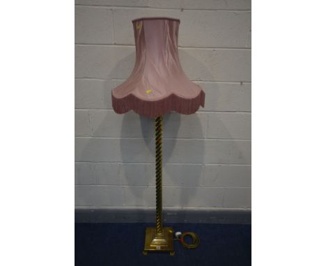 A BRASS BARLEY TWIST STANDARD LAMP on a stepped base, with claw feet, with a pink fabric shade, height to fitting 136cm