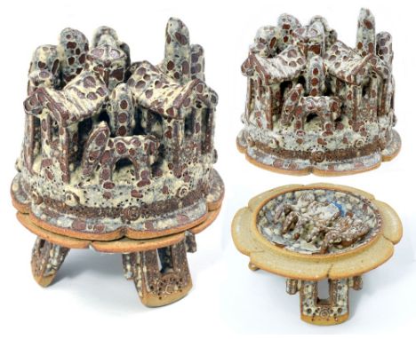 IAN GODFREY (1942-1992); a stoneware casket standing on tripod feet, the lid modelled in the form of a village of houses with