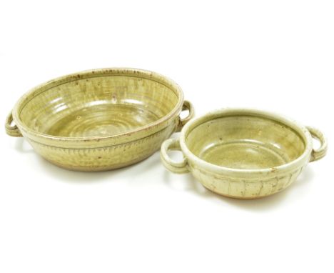RICHARD BATTERHAM (born 1936); two twin handled stoneware dishes covered in green ash glaze, largest diameter 30cm (including