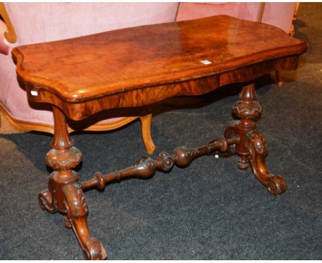 A Victorian figured walnut tea table, the moulded serpentine hinged top raised on fluted baluster turned supports, carved cab