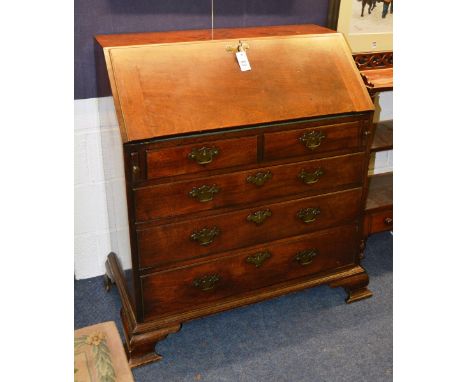 A George III mahogany bureau, the moulded fall flap with brass escutions, enclosing fitted interior, over two short and three