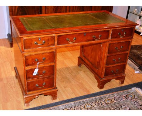 A George III style pedestal desk, the moulded rectangular top fitted with tooled skiver over three frieze drawers and banks o