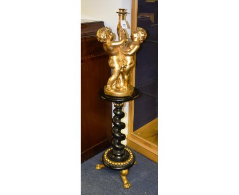 A giltwood cherub lamp, raised on ebonised stand with barley twist column on circular base and paw feet