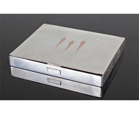 A Cartier silver and gold inlaid cigarette box. The top set with three rose gold flaming torches, with push button to the fro