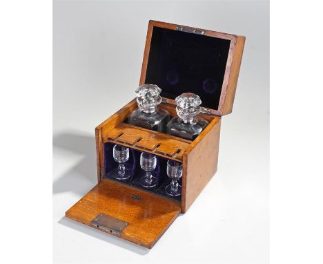 Victorian oak Tantalus in the form of a box with a flap front, the two decanters with pouring lip in divided compartments and