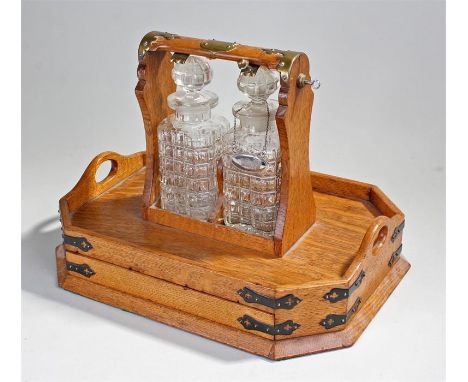 Early 20th Century oak Tantalus the tray design with two drawers below, the lock released by a button under each decanter. th