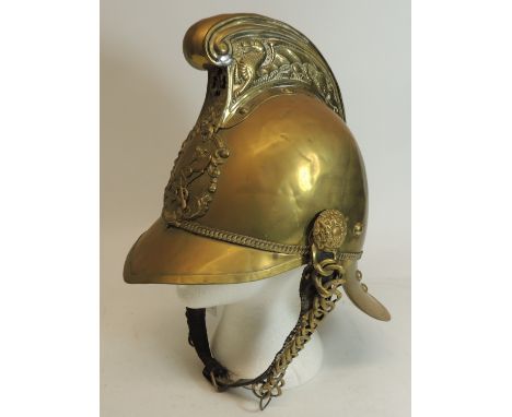 An early 20th Century brass Merryweather style fire helmet, the high comb with dragon decoration, crossed axe and hose badge 