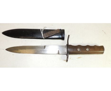 A military fighting knife with shaped wood grip, straight double edged blade and in black painted metal scabbard fitted with 