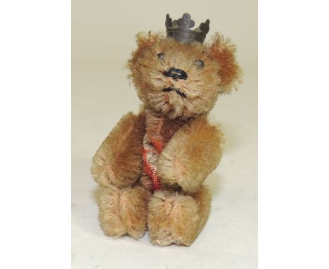 A Schuco miniature teddy bear brooch, wearing a metal crown and with cinnamon plush, metal boot button eyes, black stitched n