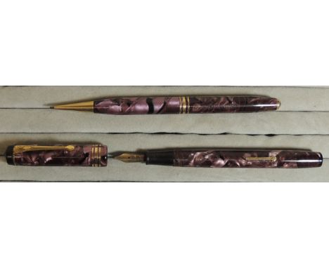 A Conway Stewart fountain pen and propelling pencil set in light pink/black marbled cases, the pen with original gold nib, c.