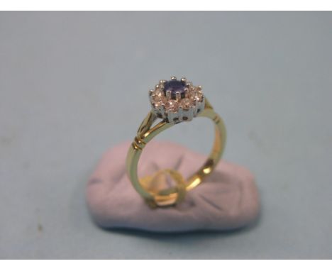 A modern 18ct. gold and diamond cluster ring, eight diamonds and central pale blue stone, claw settings, size N 