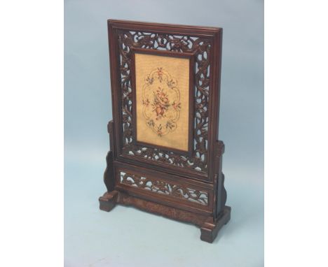A Chinese rosewood firescreen, rectangular-shape with carved and pierced dragons, inset needlework panel, stand with incised 