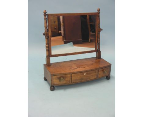 A late George III mahogany toilet mirror, rectangular plate between turned uprights, bow fronted base with three drawers, bal