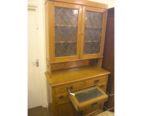 An early 20th century solid, medium oak secretaire bookcase, pair of leaded doors with stained glass panes, two adjustable sh