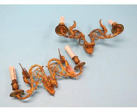 A pair of gilt-brass wall sconces, each twin-light, cast with winged females