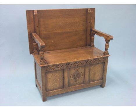 A solid, dark oak monk's bench, adjustable top above panelled box base with carved lunette border, 3ft.