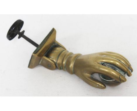 A 19th century brass door knocker formed as a hand holding a ball, length 17cm. 