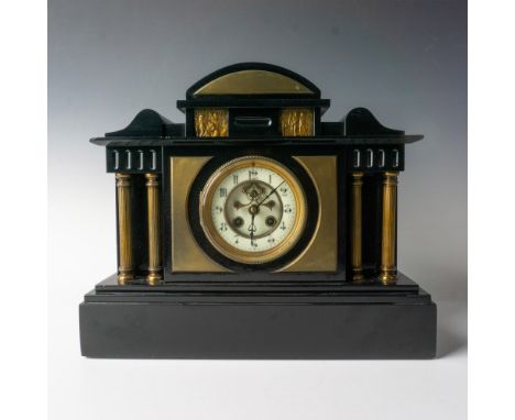 Black marble mantle clock with brass pillars and accents. The face is protected with a glass hinged door. Two small scenes wi