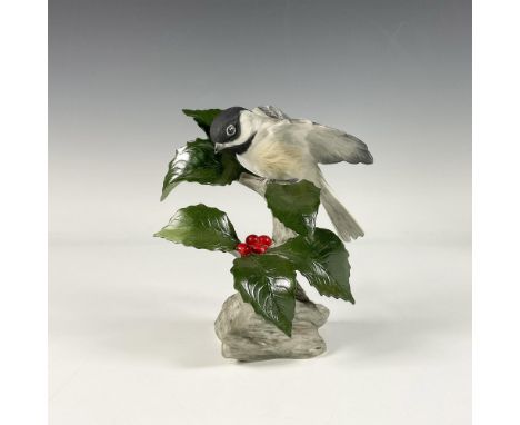 A hand painted porcelain bisque porcelain figure of a bird perched on a branch decorated with holly. Boehm backstamp. Issued: