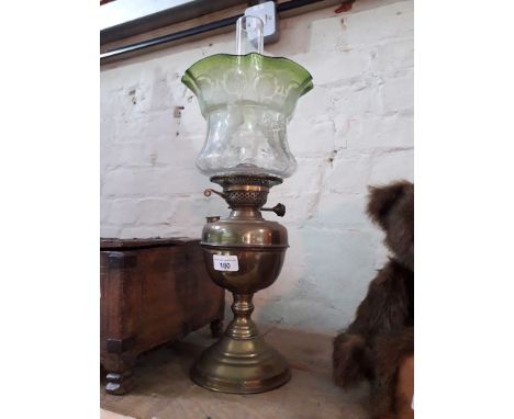 A brass oil lamp with funnel and etched green glass shade.Condition of shade:- some small nibbles to bottom edge but no sign 
