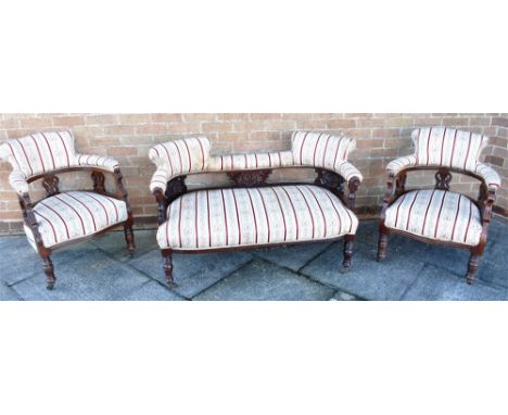 AN EDWARDIAN CARVED MAHOGANY FRAMED THREE PIECE SALON SUITE  on ring turned supports with metal casters, the sofa 140cm wide 