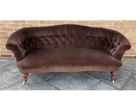 AN EDWARDIAN BUTTON UPHOLSTERED SOFA with serpentine front seat, on carved walnut supports, 190cm wide Condition Report : re-