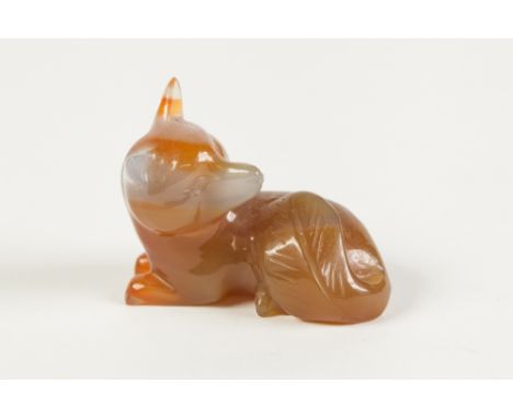 A CHINESE SMALL GREY AND RUSSET COLOURED JADE MODEL OF A RECUMBENT FOX, 2" (5cm) long 