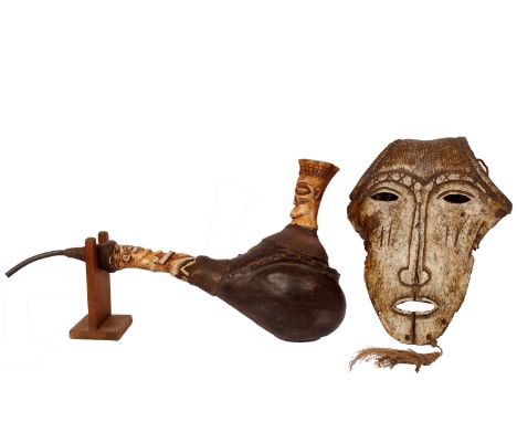 A west African tobacco pipe formed from a seed pod and carved bone together with a small mask carved from an animal skull.