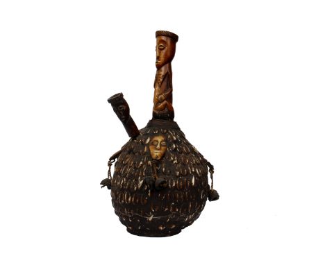 A west African tobacco pipe formed from a seed pod. Decorated throughout with cowrie shells.