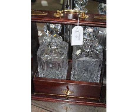 BRASS MOUNTED TWO DECANTER TANTALUS
with crystal decanters, together with a collection of coins including a silver Isle of Ma