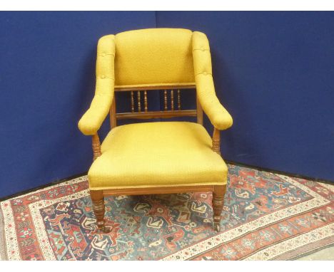 Victorian oak framed upholstered low elbow chair with spindle back and downswept button arms on turned baluster front support