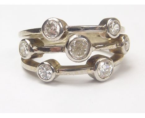 Dress ring with three bands of collet set diamond brilliants, seven in all, 9ct white gold, by Michael King. Size L. Conditio