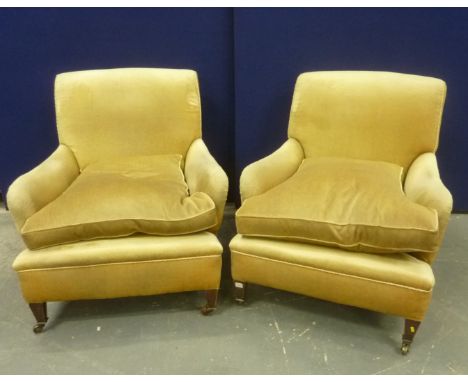 Pair of upholstered deep armchairs, each on square tapered oak supports, with brass castors. (possibly Howard, numbers 56901 