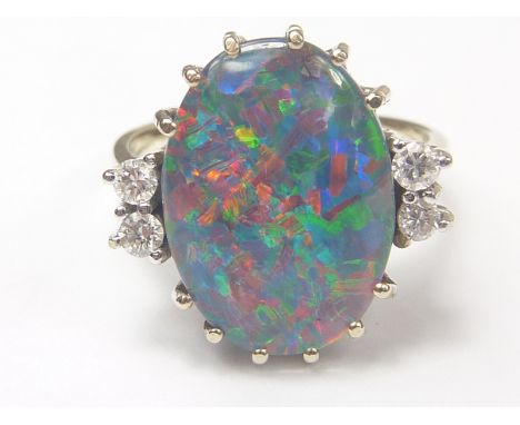 Opal ring with oval doublet flanked by four diamonds in white gold probably "750".