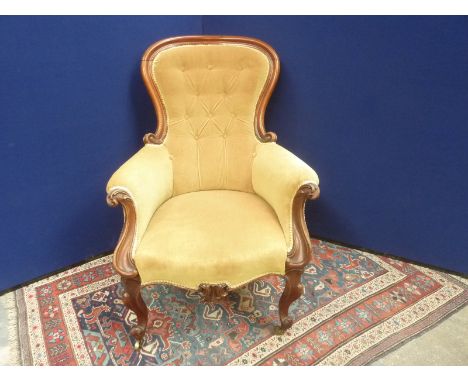 Victorian walnut framed gentleman's arm chair with button back on carved cabriole front supports with brass castors.