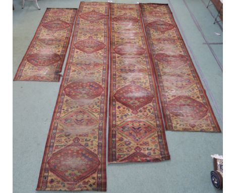 Four red ground carpet runners, 428cm, 235cm, 396cm, 356cm x 70cm wide (4) Provenance: The Late Dr Helen. E. C. Cargill Thomp