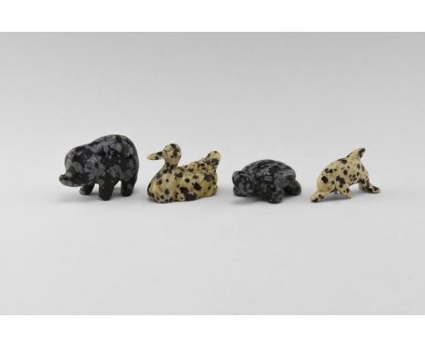 A group of four carved gemstone animals, including a pig and a turtle in snowflake obsidian, and a duck and a dolphin in spot