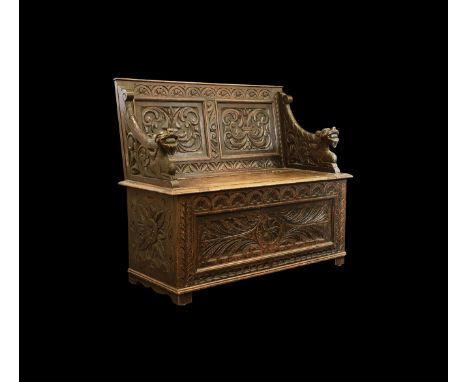 19th century AD. A carved oak bench or monk's chest with carved florid panels to the back and base, openwork arms with crouch