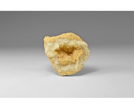 An unusual calcite geode still encased in its limestone matrix, showing two distinct growth phases: first, the cavity was lin