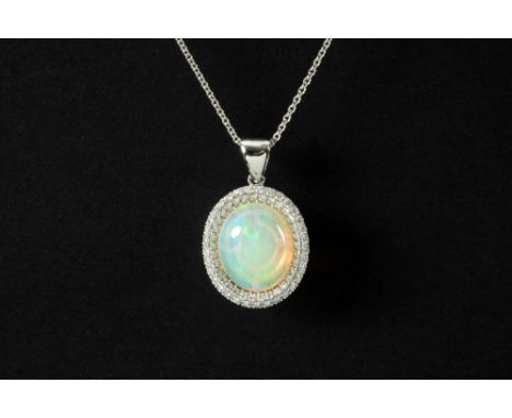 oval pendant in white gold (18 carat) with a 6,53 carat "full" cabochon cut opal surrounded by 0,76 carat of very high qualit