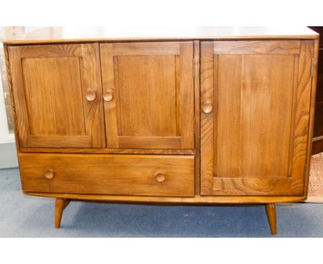 An Ercol Windsor elm sideboard, the double doored cupboard above a single drawer, beside a single cupboard door opening to re