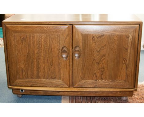 An Ercol Windsor light elm two door side cabinet, the doors opening to reveal a glass shelved interior, 91cm wide, 61cm high,