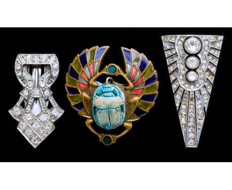 A 1920s Egyptian revival scarab beetle brooch, set with a ceramic scarab within an enamelled metal mount, together with two A
