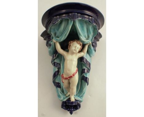 A 19th century Majolica Wedgwood wall shelf, modelled putti and draped curtains on a blue ground, height 10ins - there is a s