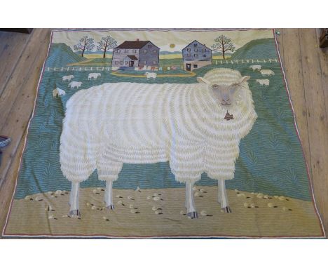A large crewel work tapestry wall hanging, of a sheep in a field with further sheep behind and buildings to the background, 6